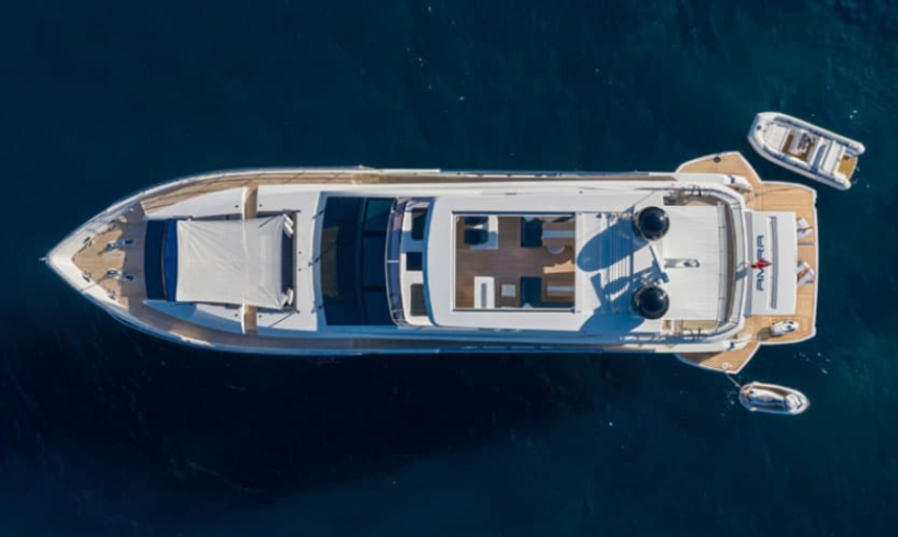 Luxury yacht sailing through crystal blue waters with white sails unfurled against a clear sky