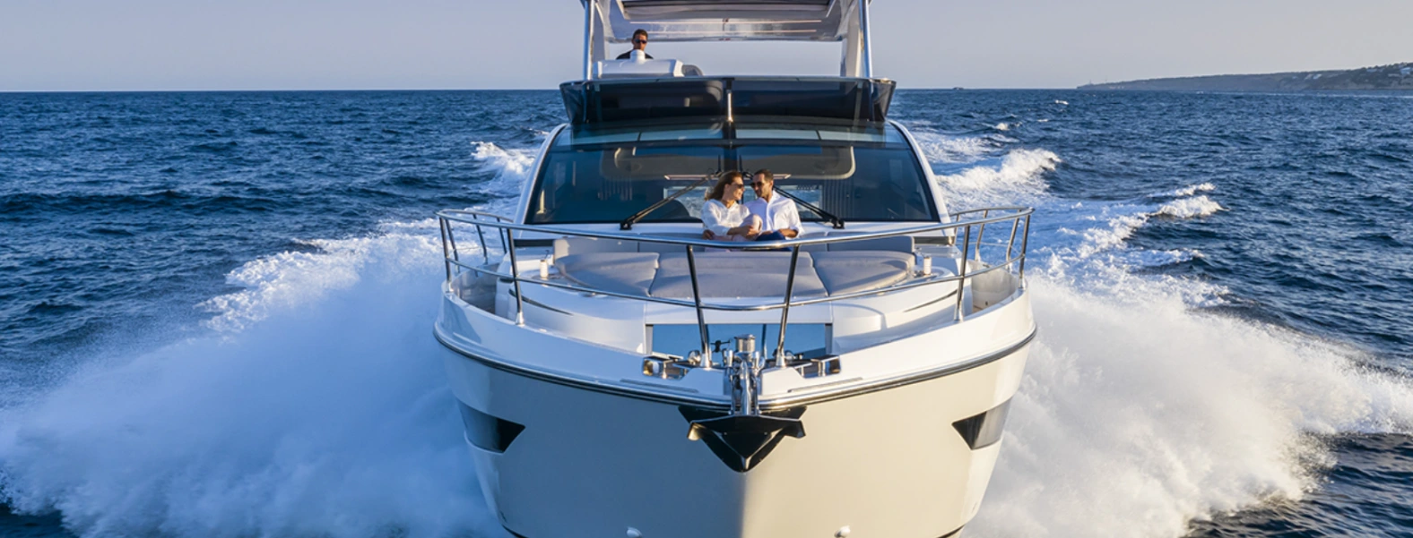 Modern yacht interior with elegant white leather seating and panoramic ocean views through large windows